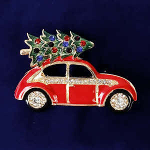Festive red beetle-style car brooch by Indulgence with diamante wheels and a Christmas tree decorated with sparkling red and blue baubles.